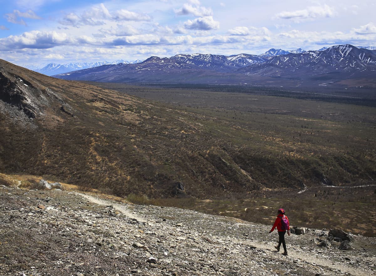 Hiker layering up along an exposed alpine trail