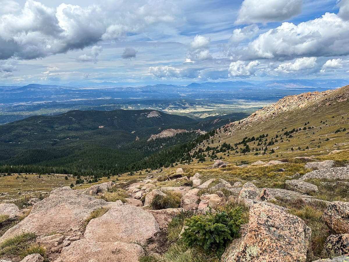 Alpine tundra and granite outcrops on the upper mountain, with the plains stretching out toward the horizon