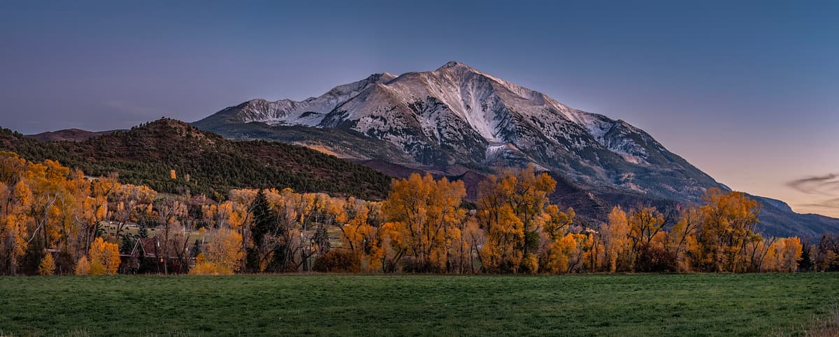 Mount Sopris at dusk above golden cottonwoods and a green pasture in the Roaring Fork Valley near Carbondale, Colorado