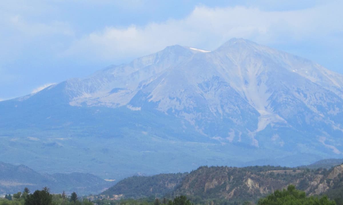 The twin summits of Mount Sopris seen from the north on a hazy summer day, with the connecting saddle visible between them