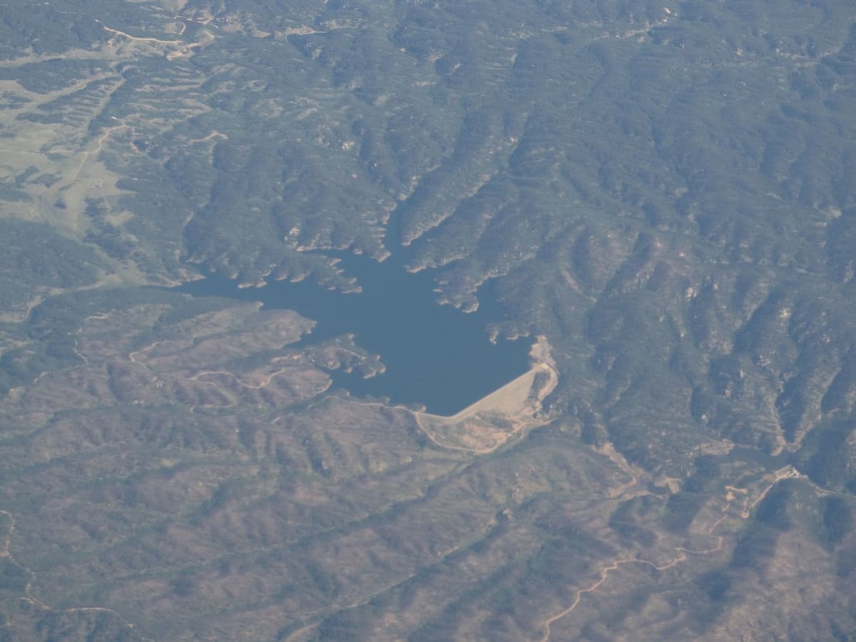 A wide view across Rampart Reservoir ringed by pine forest under a blue Colorado sky