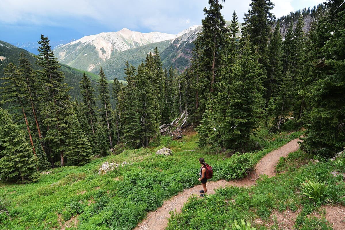 A hiker climbing the trail toward Lower Ice Lake Basin above South Mineral Campground in the San Juan National Forest