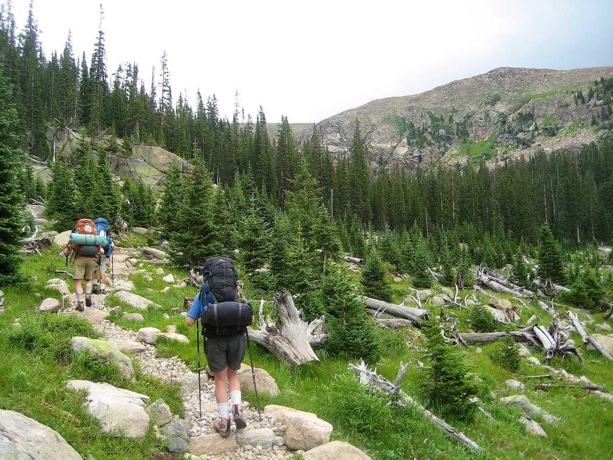Hikers moving along an exposed Colorado trail in full layered outfits
