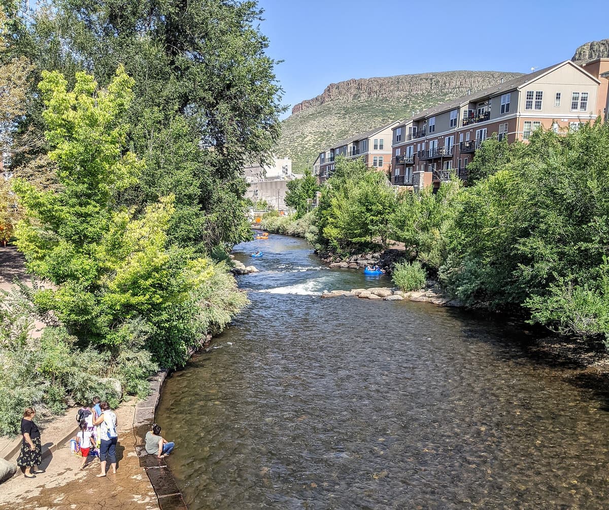 Tubers floating Clear Creek in downtown Golden, Colorado, with a table mountain rising behind the town